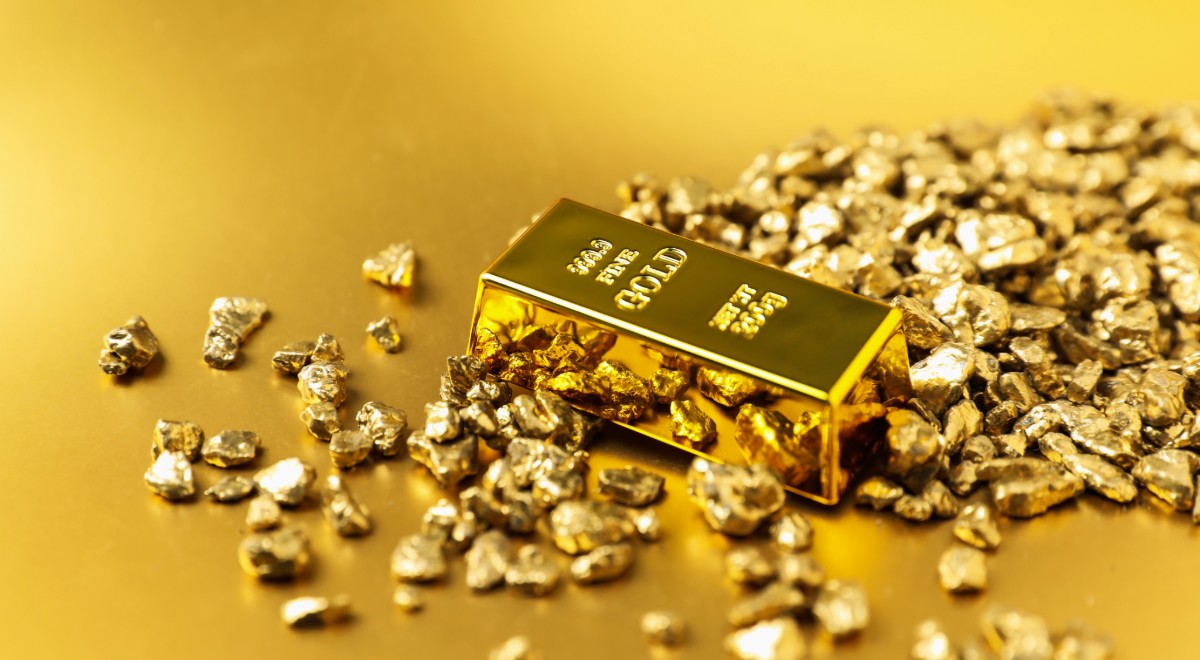 Pepitas de oro y barra sobre fondo brillante
