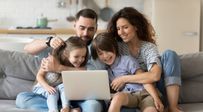 Familias con niños pequeños pasan el tiempo juntos sentados en el sofá en la sala de estar con laptop