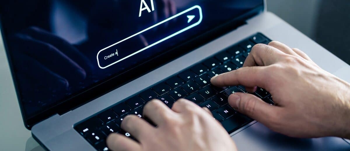 Hombre usando chatbot con laptop en el trabajo. Imagen de Shutterstock