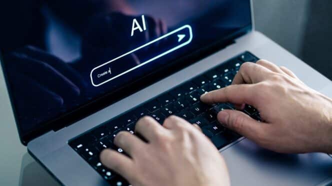 Hombre usando chatbot con laptop en el trabajo. Imagen de Shutterstock