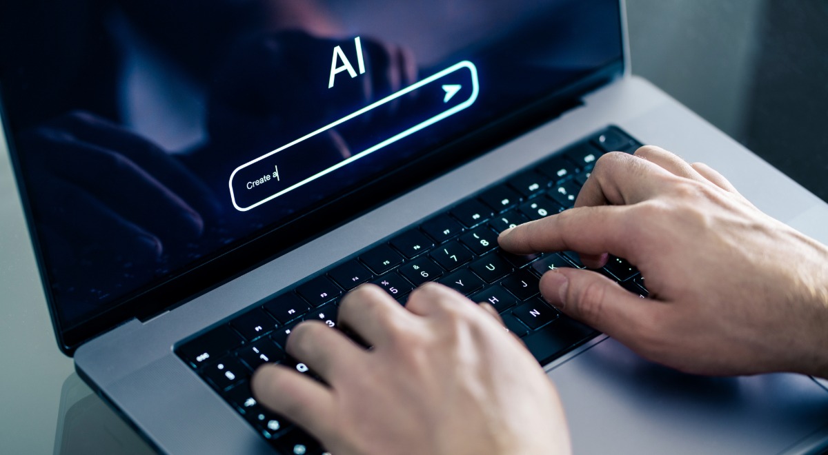 Hombre usando chatbot con laptop en el trabajo. Imagen de Shutterstock