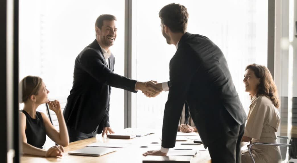 Dos personas en traje dándose la mano