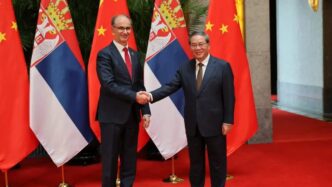 El primer ministro de China, Li Qiang y el primer ministro de Serbia, Đuro Macut, dándose la mano.